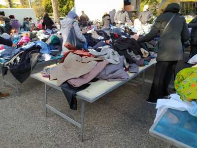 Al fianco di tavoli ricolmi di vecchi maglioni e vestiti di seconda mano...